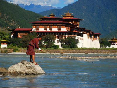 A man removes a plastic bottle from a river in Punakha, Bhutan, clearing litter deposited during a festival from days earlier. Pictured in the background is Punakha Dzong which houses Buddhist temples and the administrative offices of Punakha district.