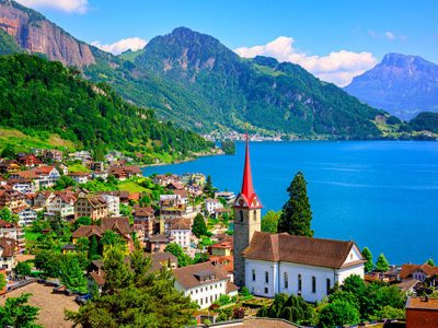 Little swiss town with gothic church on Lake Lucerne and Alps mountain, Switzerland.